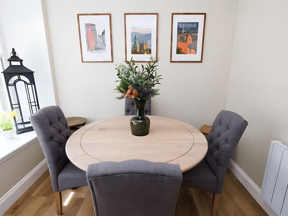 A dining room with a round table and chairs at Robert the Bruce Apartment in Dunfermline