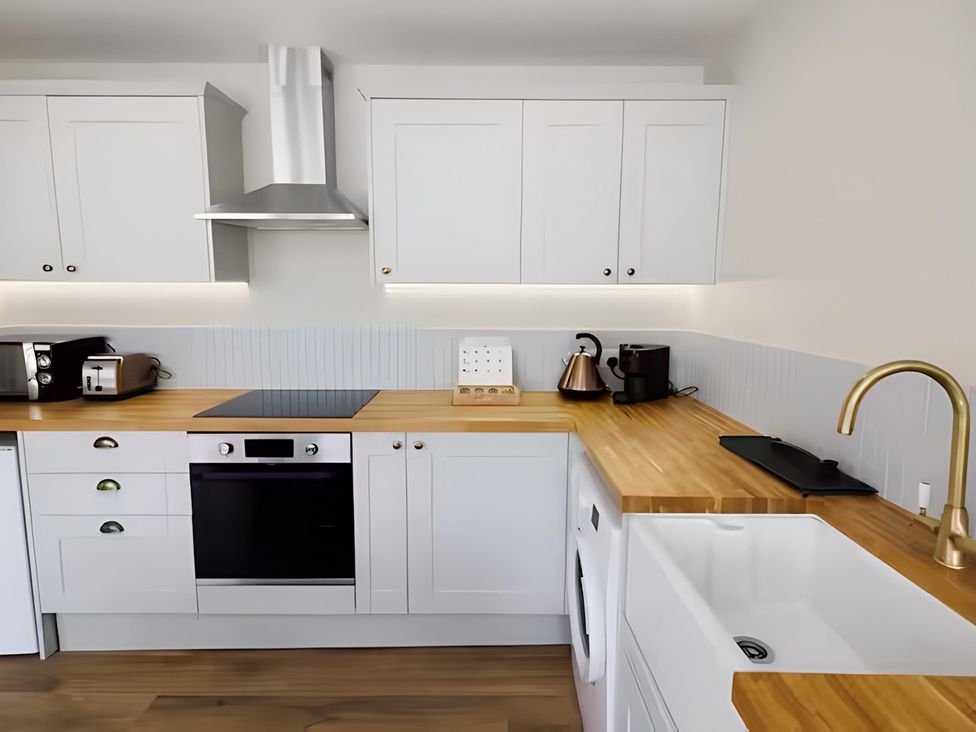 A kitchen with cabinets, countertop, oven, stovetop, sink and appliances at Robert the Bruce Apartment, Dunfermline
