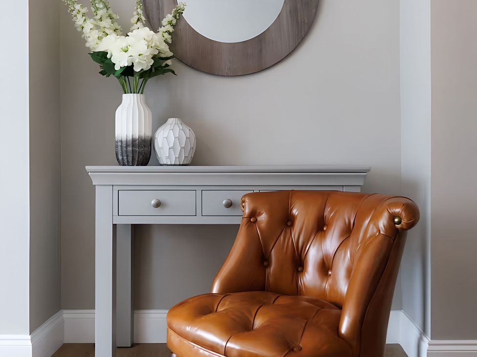 An entrance area with a chair, table, vase, and mirror at Robert the Bruce Apartment Dunfermline