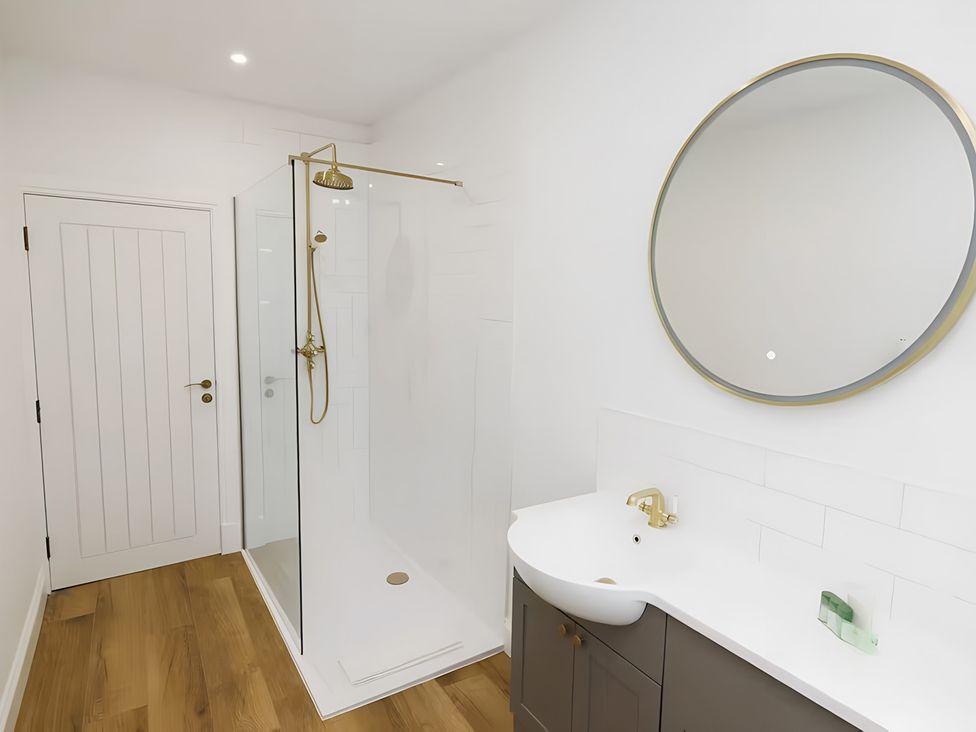 A bathroom with a shower, mirror, and sink at Robert the Bruce Apartment in Dunfermline