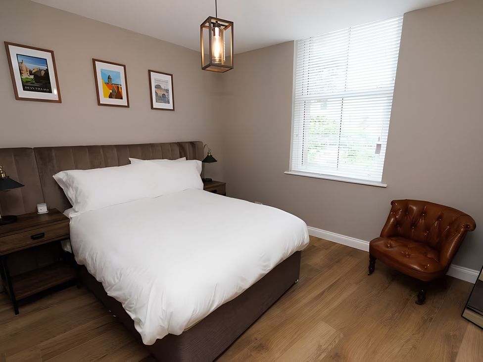 A bedroom with a bed and a small chair at Robert the Bruce Apartment in Dunfermline