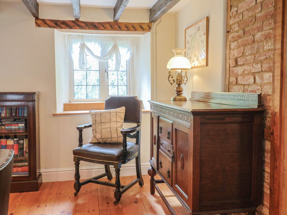 A sitting room with a chair and lamp at Ellishayes Farm in Combe Raleigh