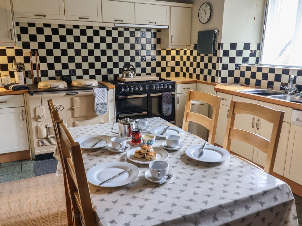 A kitchen with an oven, stove, and a dining table set for tea at Ellishayes Farm in Combe Raleigh