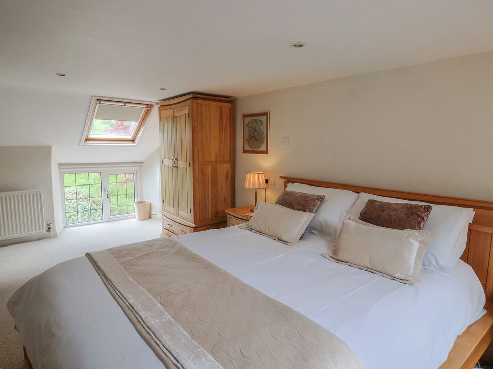 A bedroom with a bed, wardrobe, and window at Ellishayes Farm in Combe Raleigh