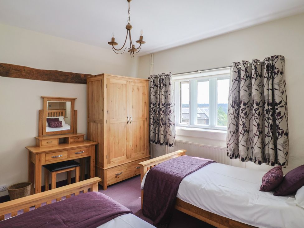 A bedroom with beds, wardrobe, and window at Ellishayes Farm in Combe Raleigh