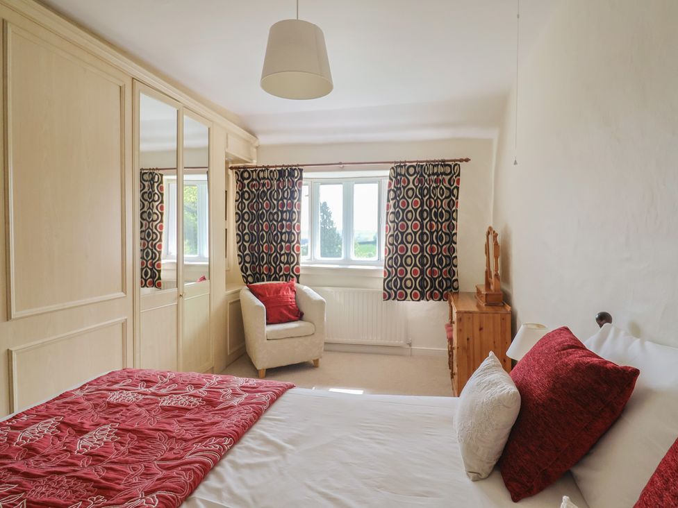 A bedroom with a bed and armchair at Ellishayes Farm in Combe Raleigh
