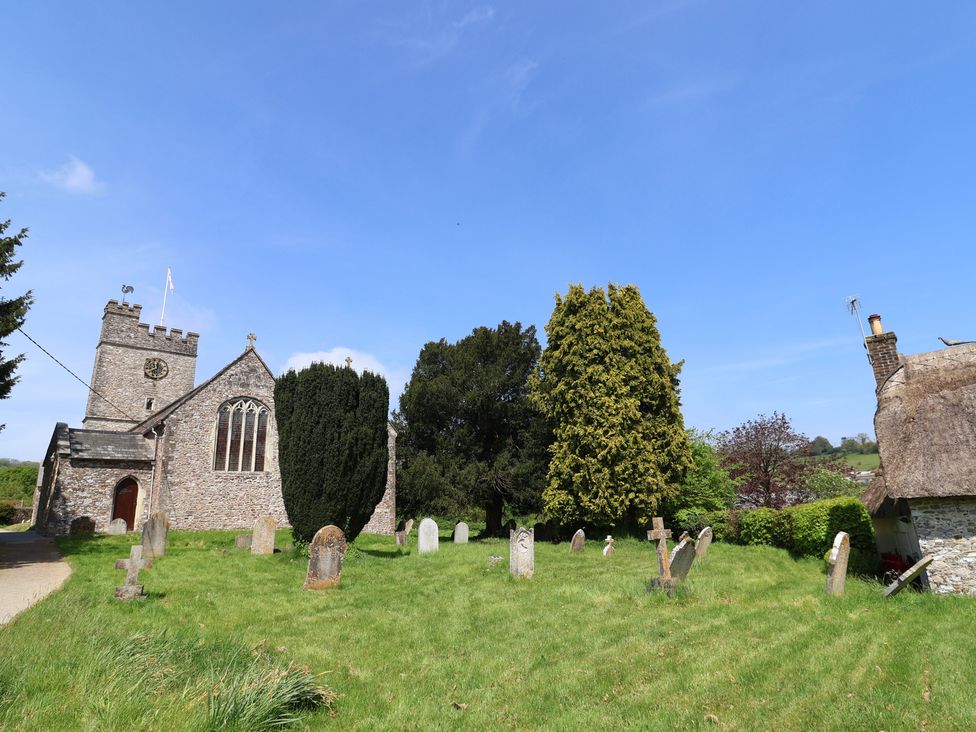 A church with a graveyard and trees at Ellishayes Farm in Combe Raleigh