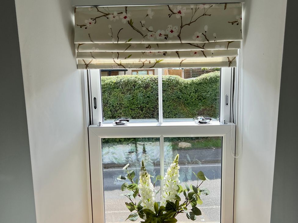 A window with a flower arrangement and outdoor view at Penderyn Cottage Aberdare