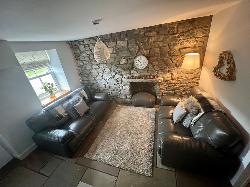 A living room with sofas and a stone wall at Penderyn Cottage in Aberdare