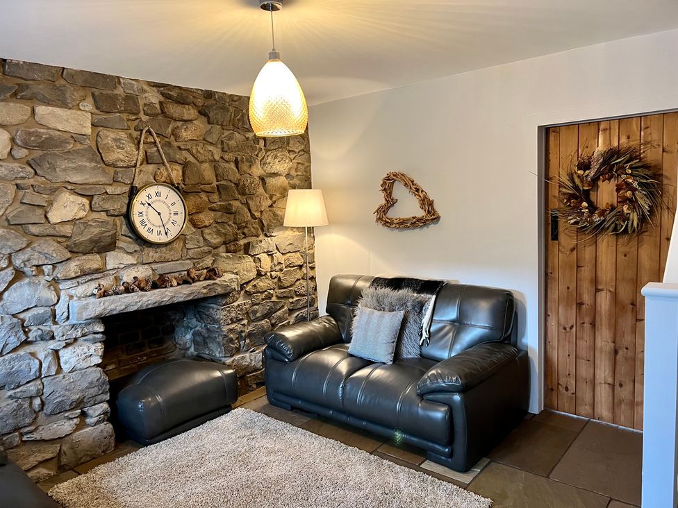 A living room with a sofa and a fireplace at Penderyn Cottage in Aberdare