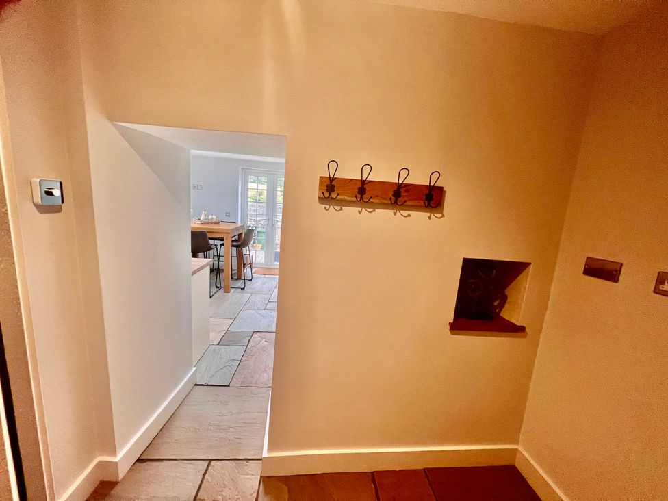 A hallway with hooks on the wall leading to a kitchen at Penderyn Cottage Aberdare