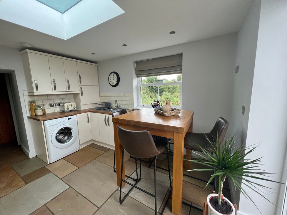 A kitchen with cabinets and a dining table at Penderyn Cottage Aberdare