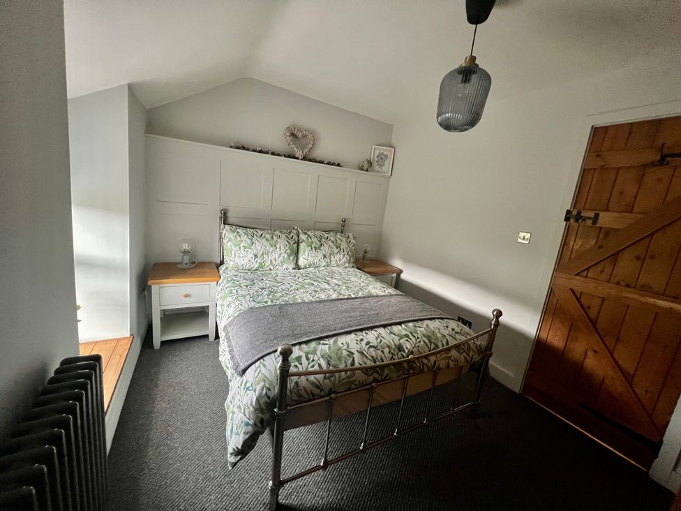 A bedroom with a bed and bedside table at Penderyn Cottage Aberdare