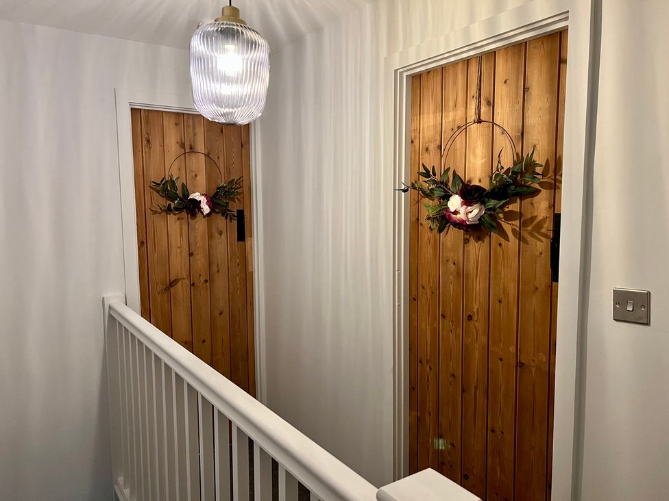 A hallway with two wooden doors decorated with wreaths at Penderyn Cottage Aberdare
