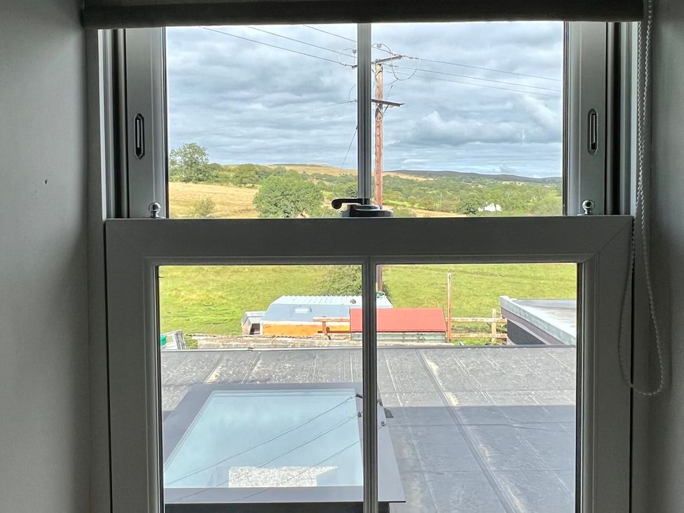 A window view showing fields and rooftops at Penderyn Cottage in Aberdare