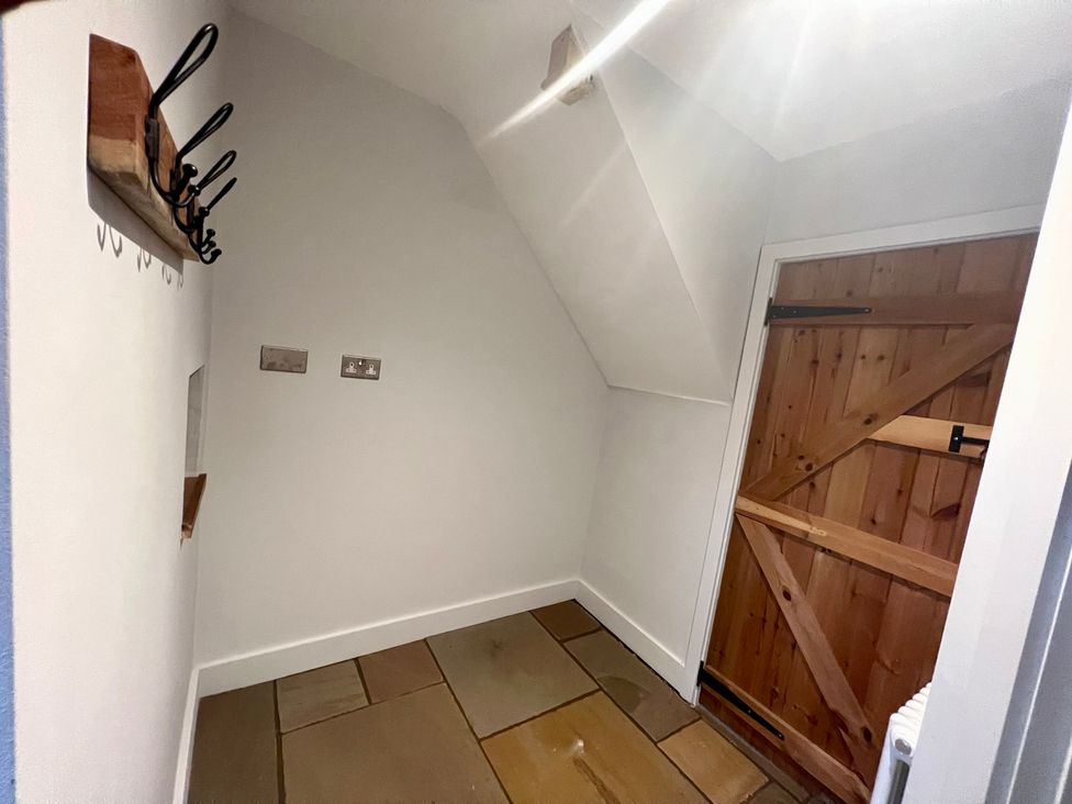 An entryway with hooks on the wall and a wooden door at Penderyn Cottage Aberdare