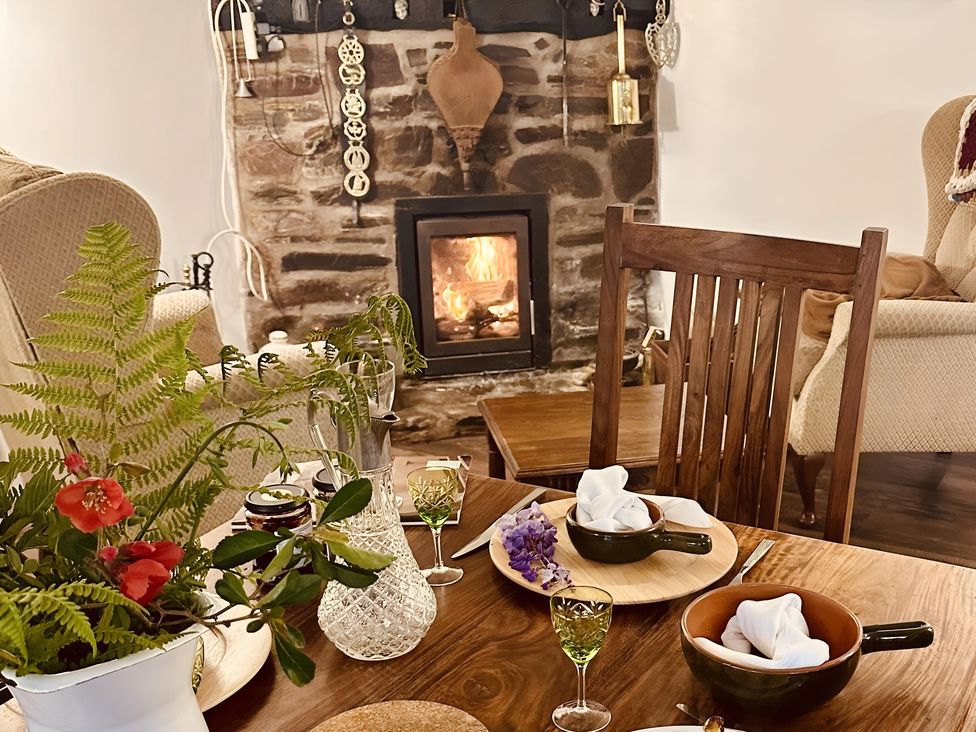 A dining room with a fireplace and a wooden table set at The Bark House in Tiverton