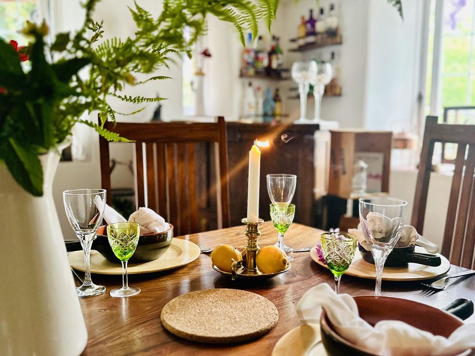 A dining room table set with dinnerware and a candle at The Bark House in Tiverton