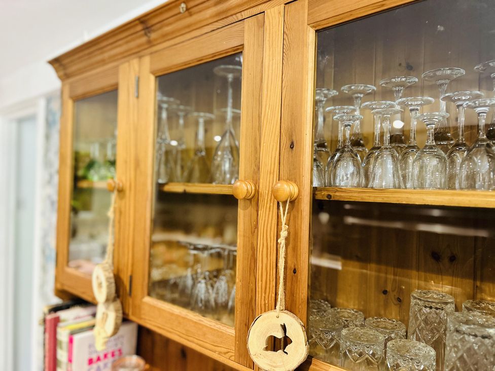 A wooden cabinet with glassware in a kitchen at The Bark House in Tiverton