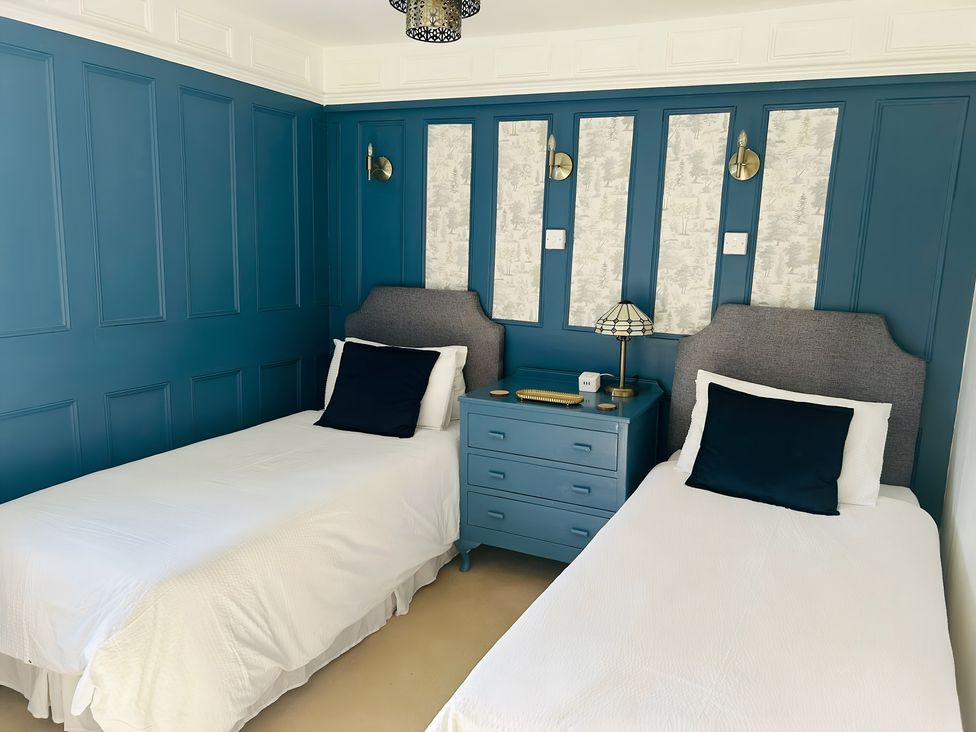 A bedroom with two beds and a lamp on a nightstand at The Bark House in Tiverton