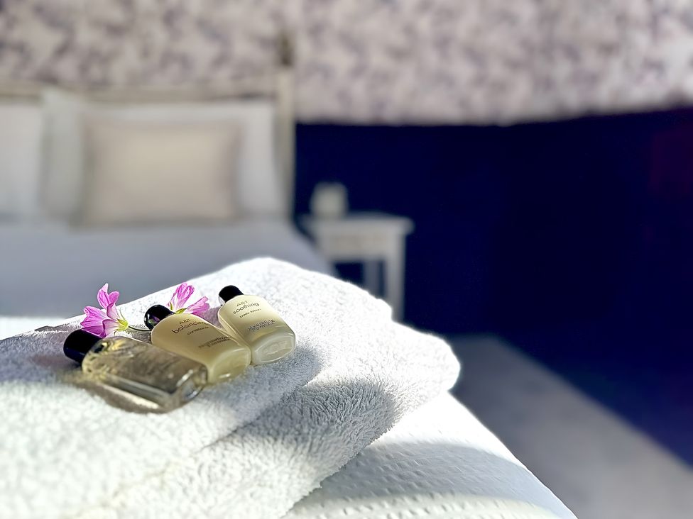 A towel with toiletries and flowers in a bedroom at The Bark House in Tiverton