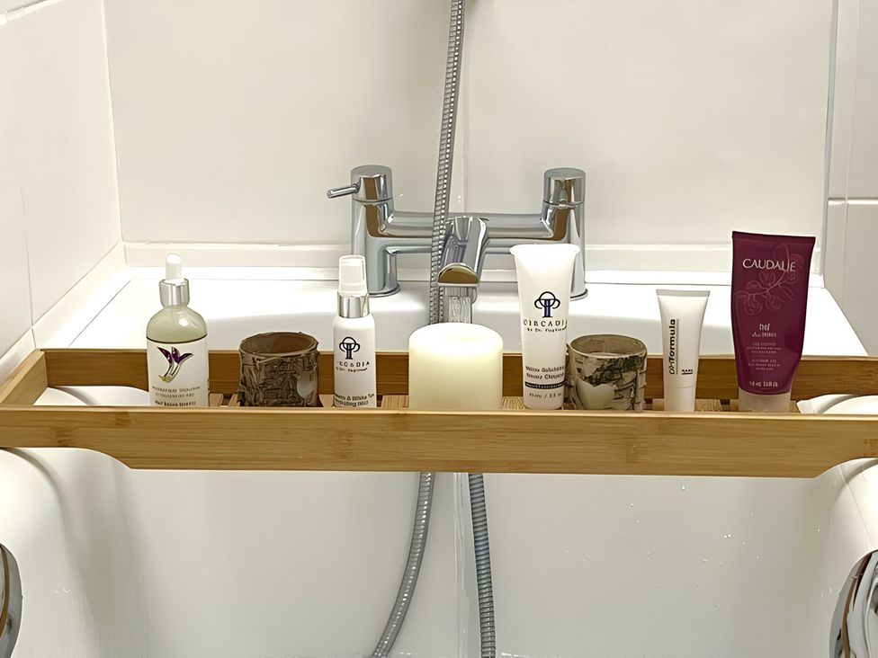 A bathtub with a bamboo tray holding skincare products at The Bark House in Tiverton