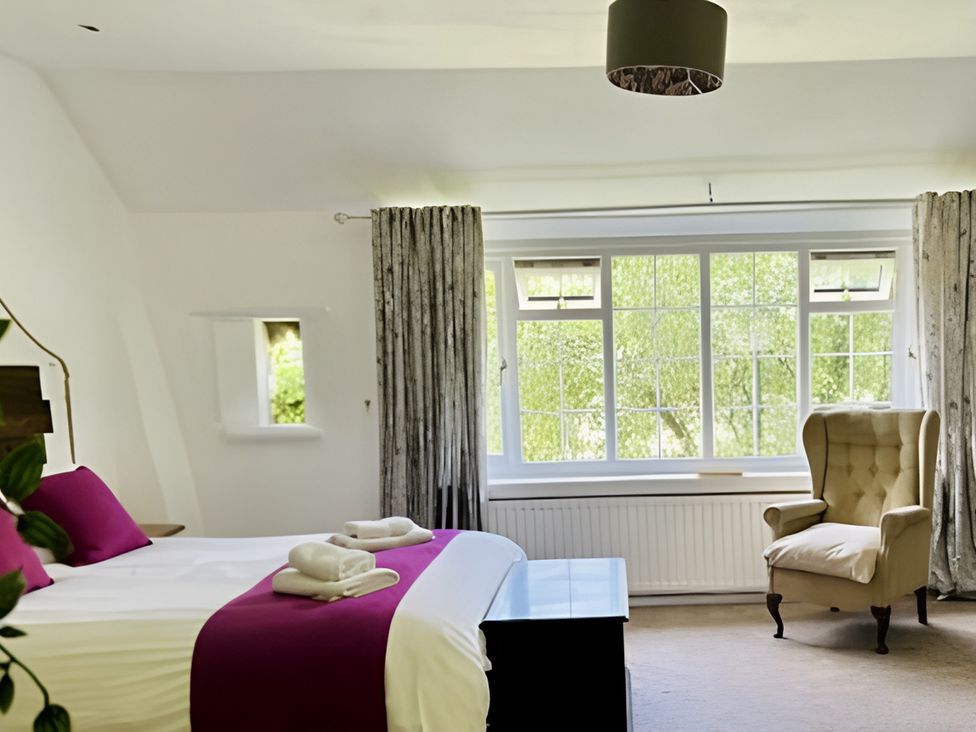 A bedroom with a bed and a chair at The Bark House in Tiverton
