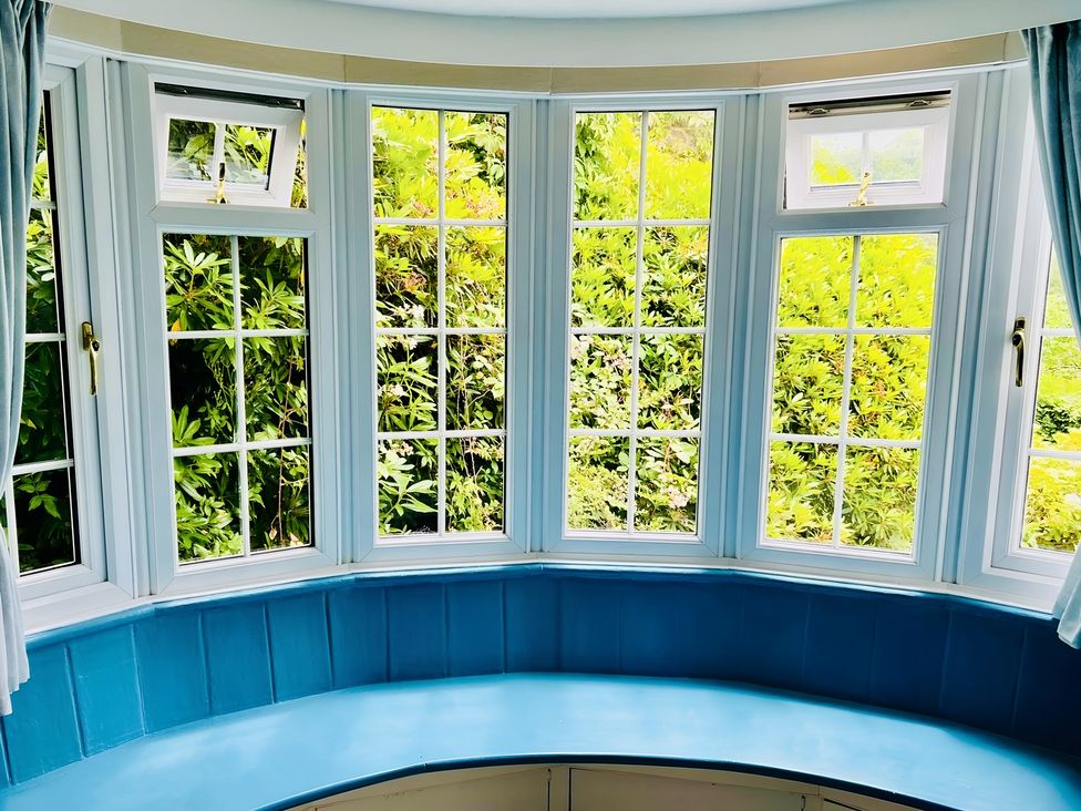 A living room with bay windows and greenery visible at The Bark House in Tiverton
