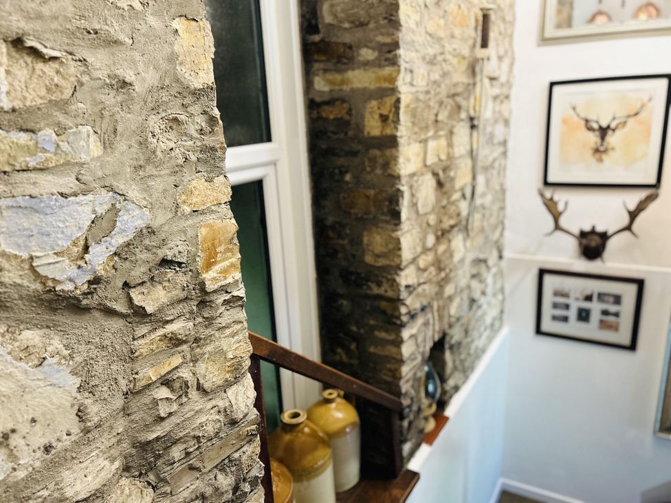 A staircase with stone walls and decorative items at The Bark House in Tiverton
