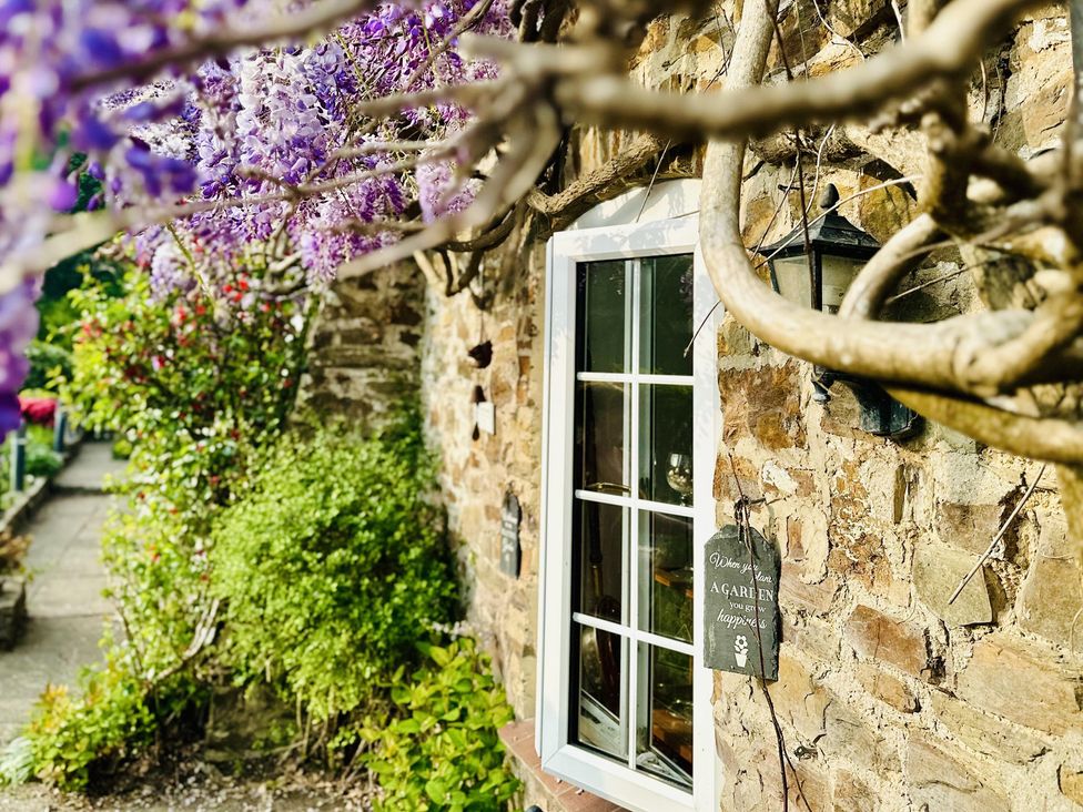 A window with a stone wall and flowering plants at The Bark House in Tiverton