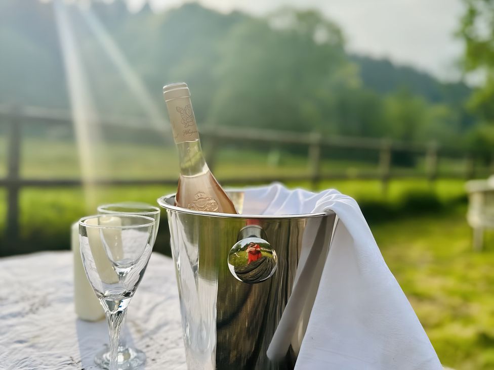 An ice bucket with wine and glasses on a table outdoors at The Bark House in Tiverton