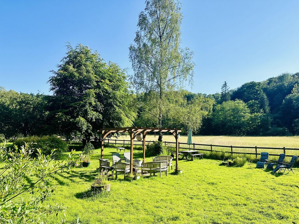 An outdoor seating area with a pergola and trees at The Bark House in Tiverton
