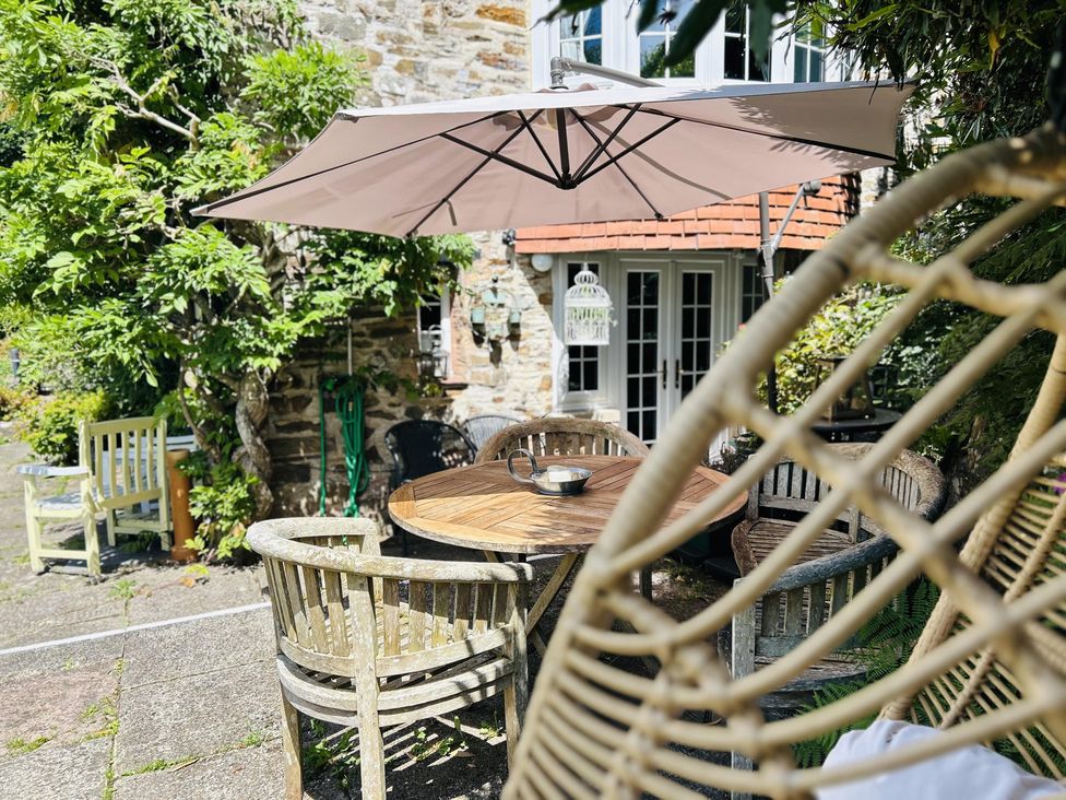A garden with table and chairs under an umbrella at The Bark House in Tiverton