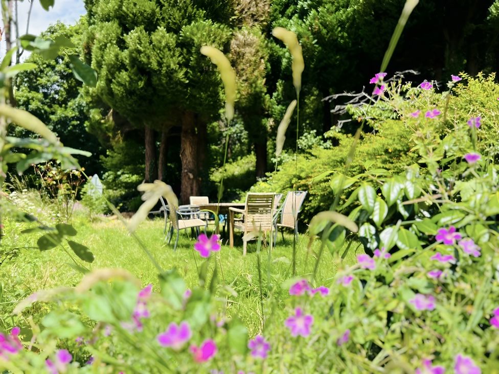 A garden with flowers and a seating area at The Bark House in Tiverton
