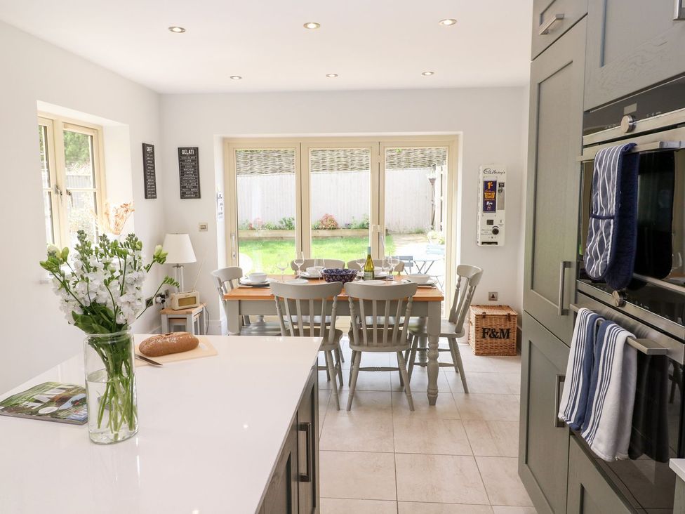 A kitchen with a dining area and a vase of flowers at East View in Cheltenham
