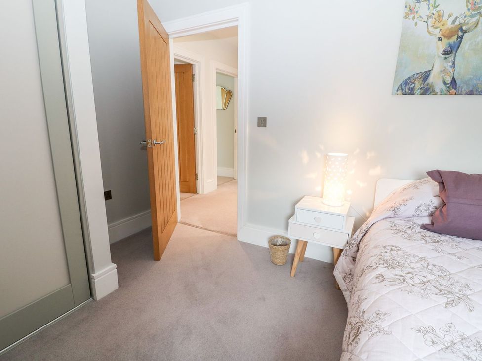 A bedroom with a bed, lamp, and nightstand at East View Cheltenham
