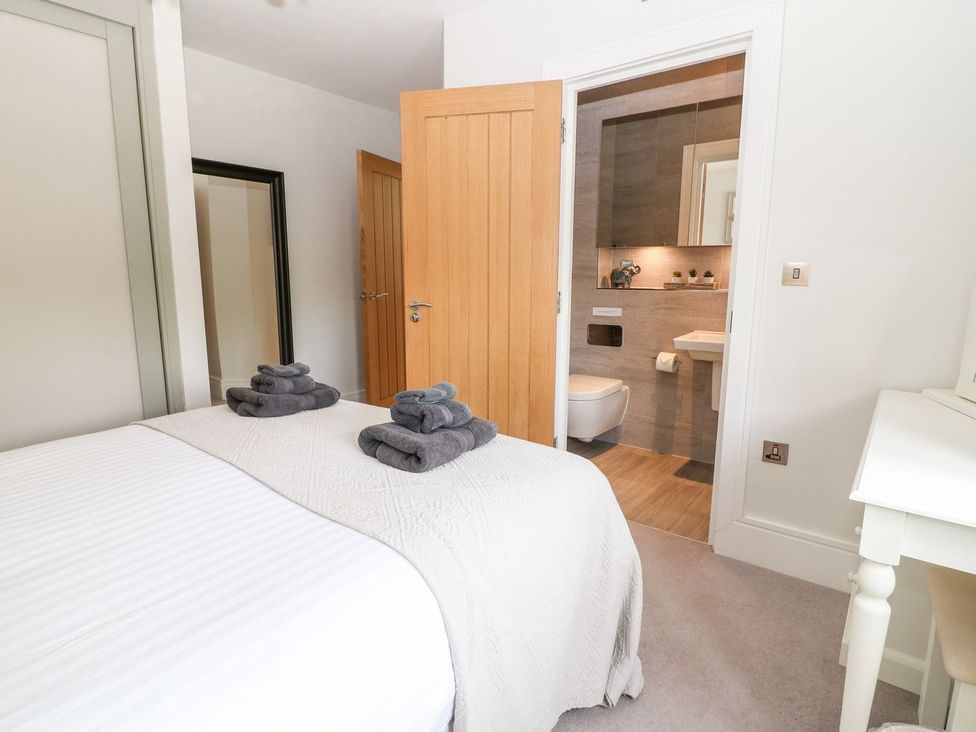 A bedroom with towels on the bed and a bathroom door at East View in Cheltenham