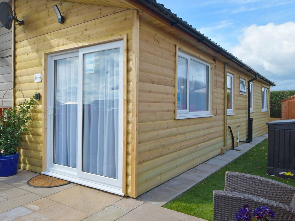 An exterior view of a wooden house with a door and windows at 228b Eighth Avenue in Bridlington