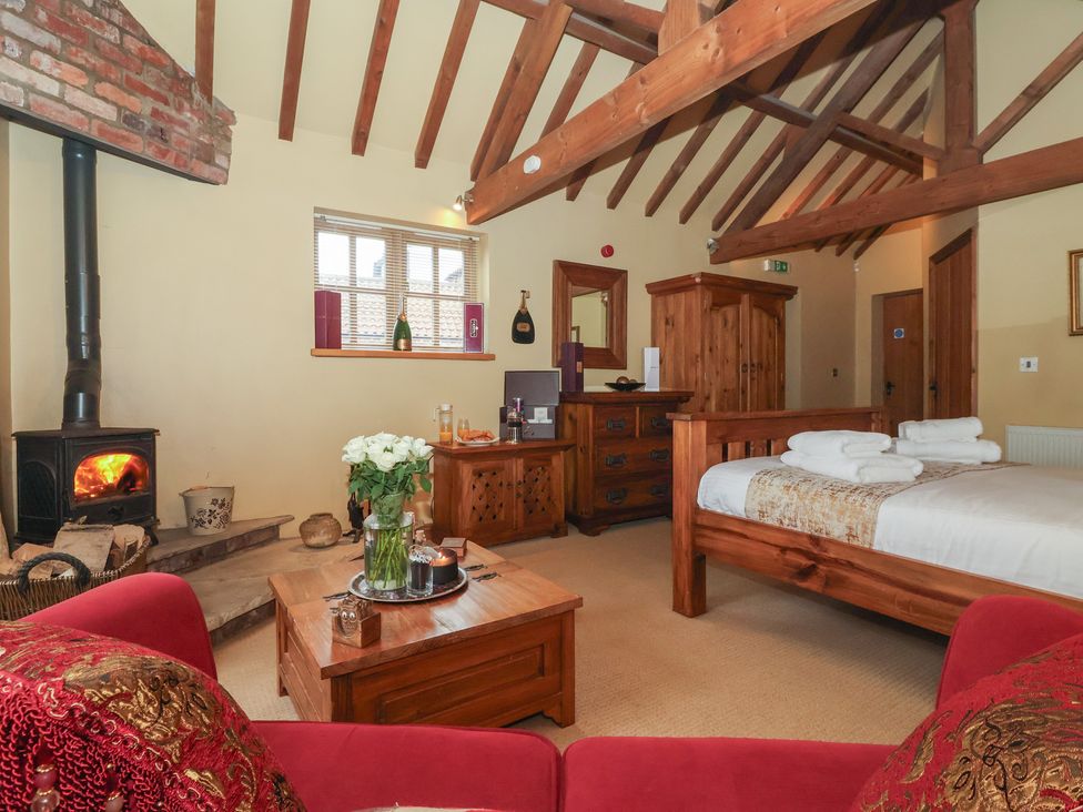 A bedroom with a wooden bed and fireplace at Champagne Cottage in Malton