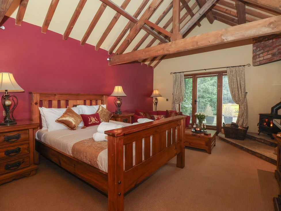 A bedroom with a wooden bed and sofa at Champagne Cottage in Malton