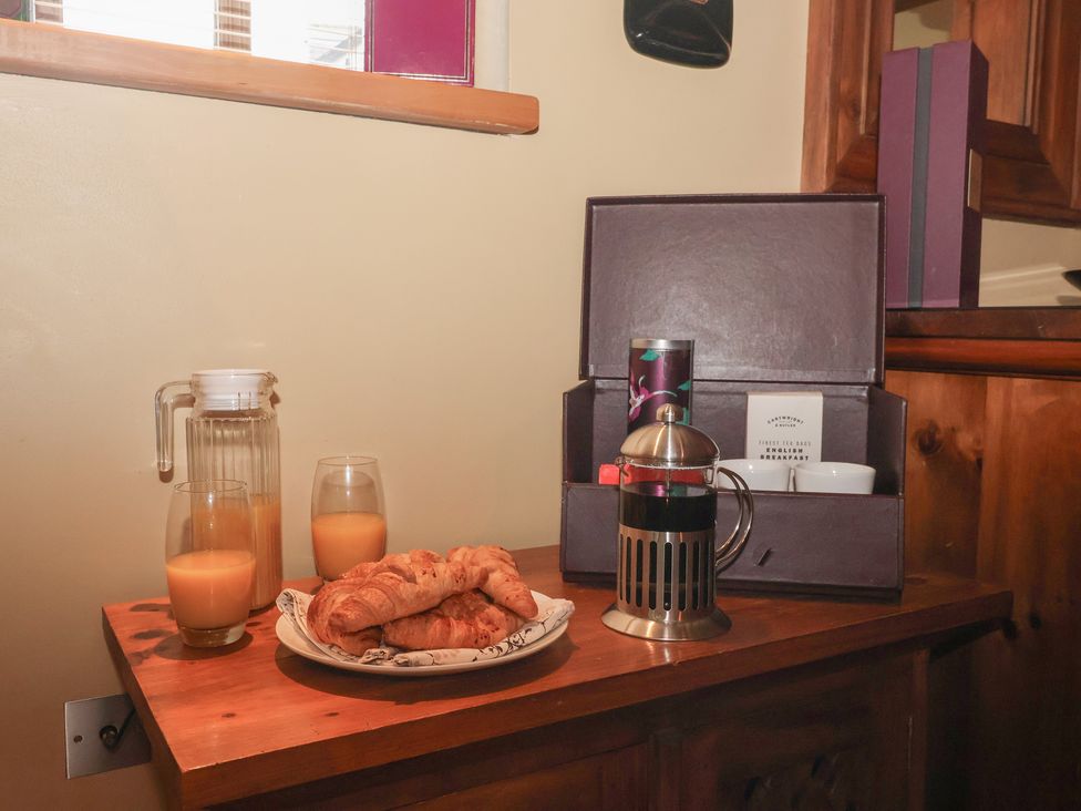 A kitchen counter with coffee, juice, and croissants at Champagne Cottage in Malton