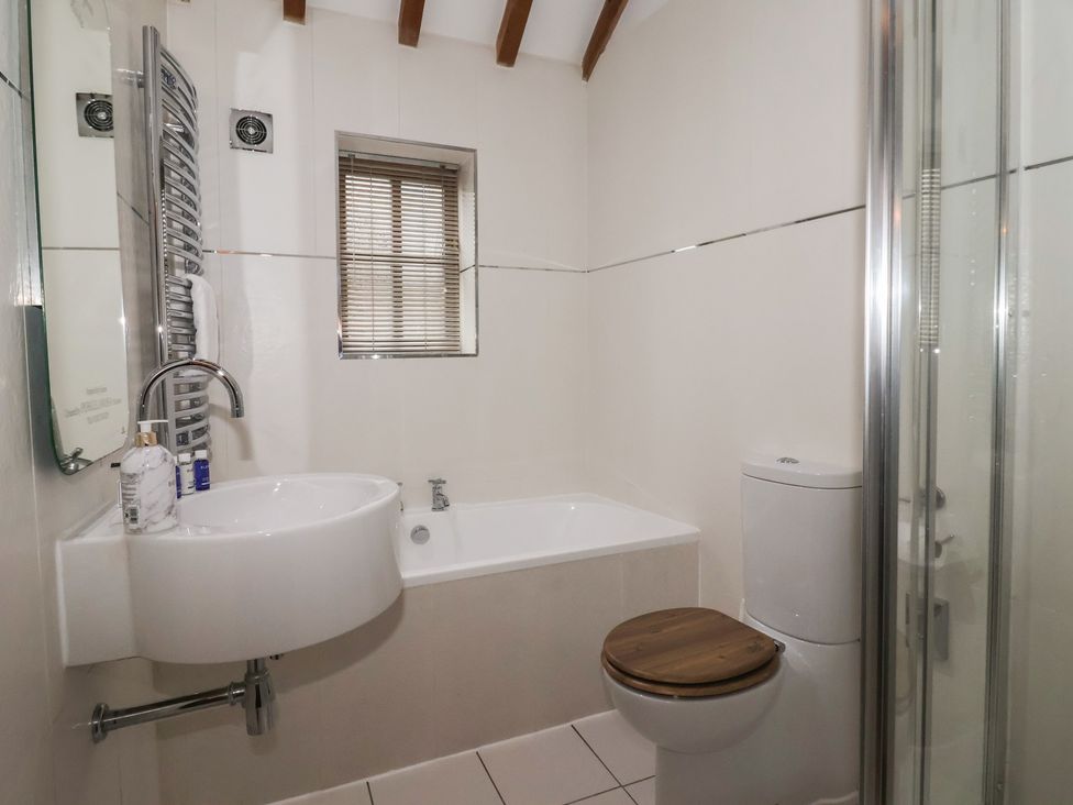 A bathroom with a sink, bathtub, toilet, and shower at Champagne Cottage in Malton