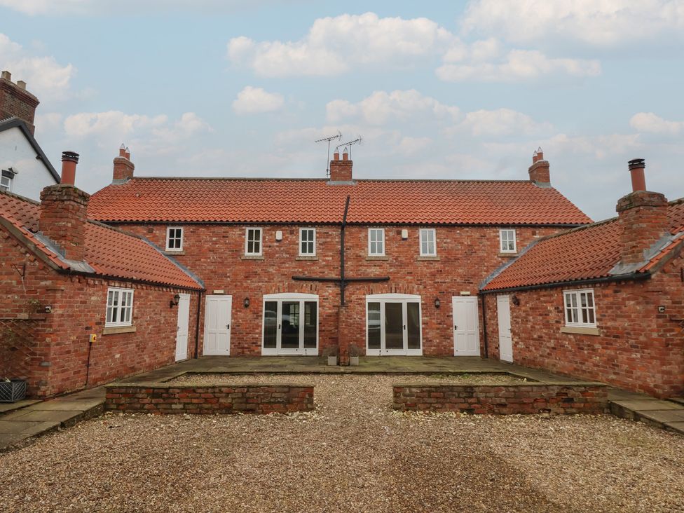 An outdoor view of a brick building with multiple entrances and windows at Champagne Cottage in Weaverthorpe