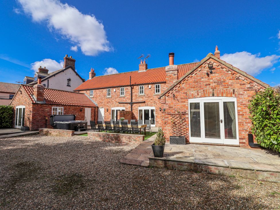 An outdoor area with a brick house and seating at Champagne Cottage in Weaverthorpe