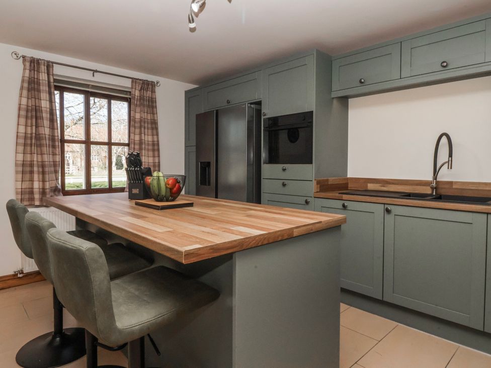 A kitchen with a refrigerator and bar stools at Champagne Cottage in Weaverthorpe
