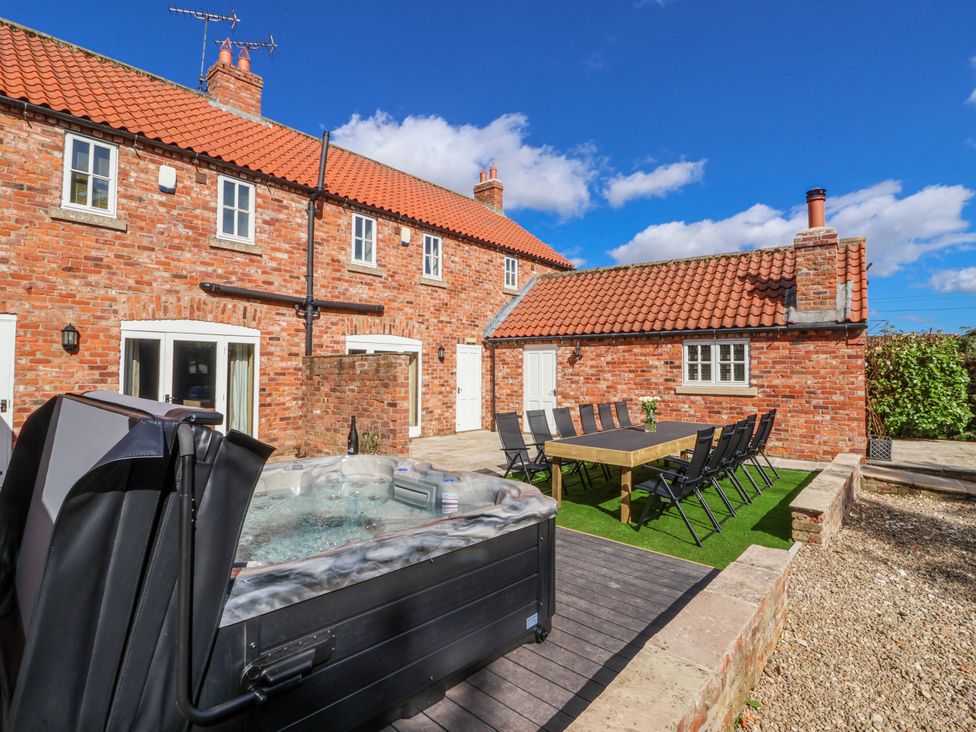 An outdoor seating area with a hot tub and dining table at Champagne Cottage in Weaverthorpe