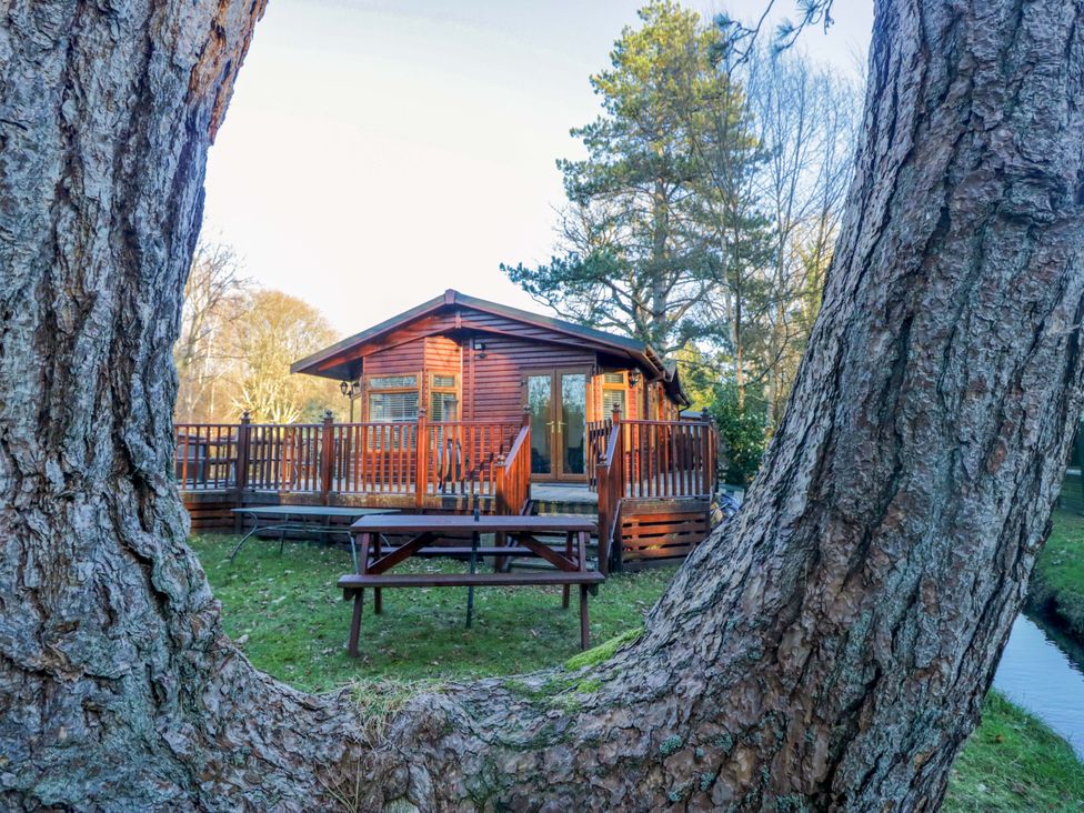 A log cabin with a decking area and picnic table at 6 Waterside in Windermere
