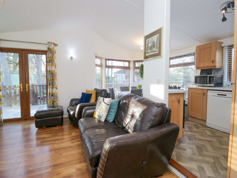 A living room with a sofa, armchair, and kitchen units at 6 Waterside Windermere