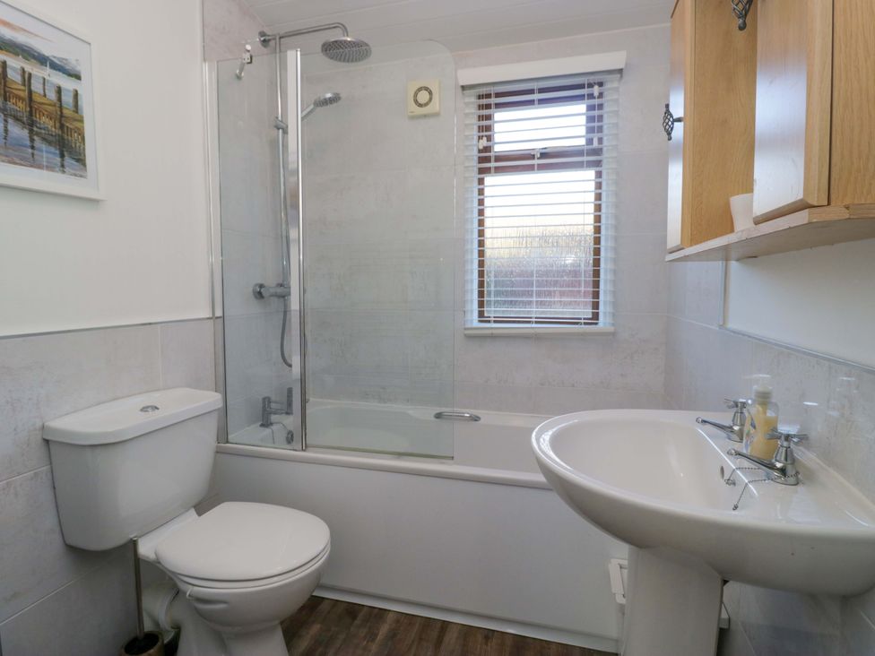 A bathroom with a bathtub, shower, toilet, and sink at 6 Waterside in Windermere