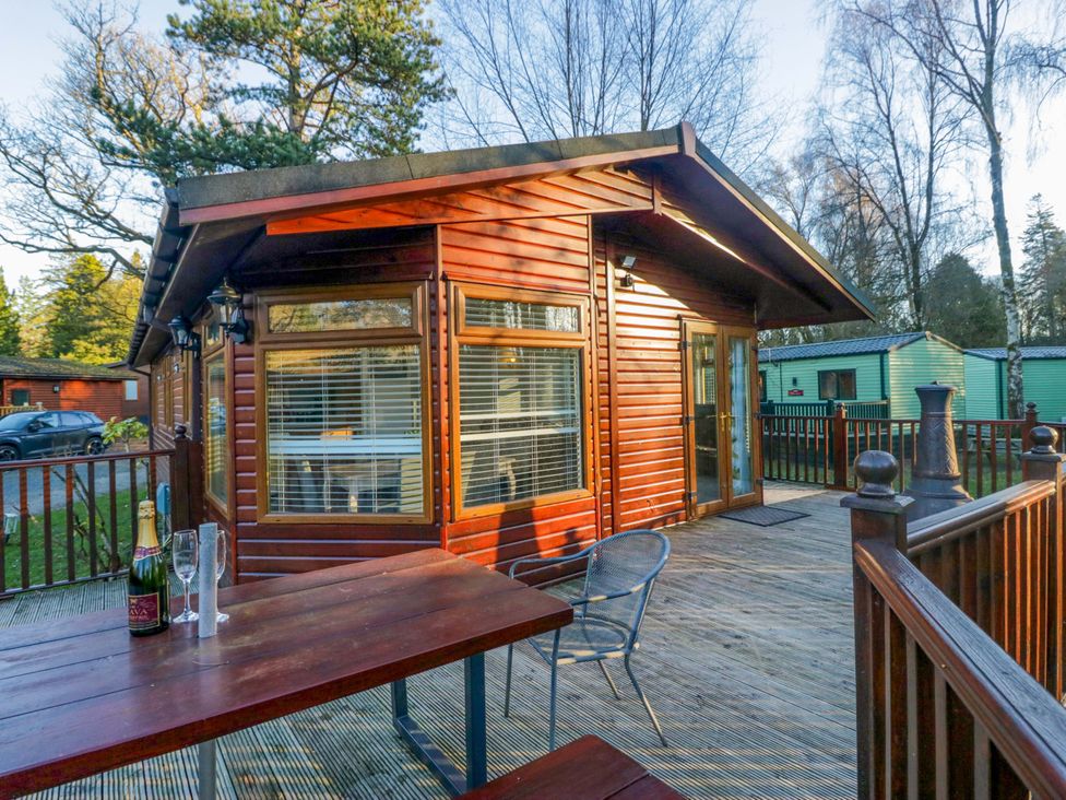 A log cabin with a deck and table at 6 Waterside Windermere